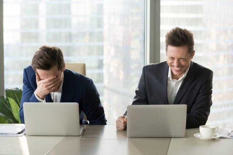 Two workers laughing in front of their laptops
